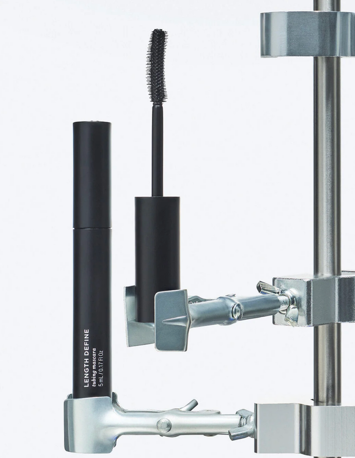 Black mascara and eyeliner with a metal stand on a white background