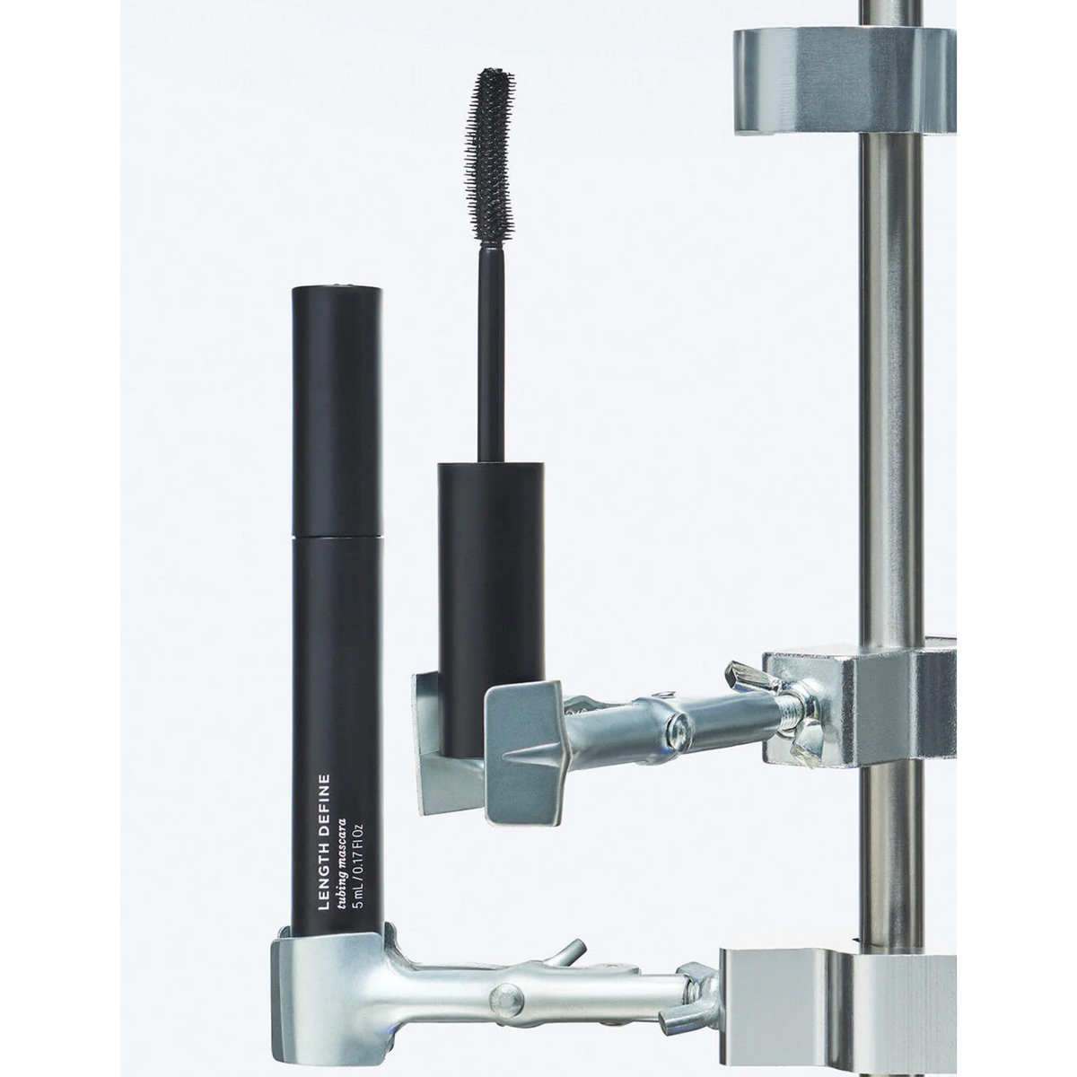 Black mascara and eyeliner with a metal stand on a white background