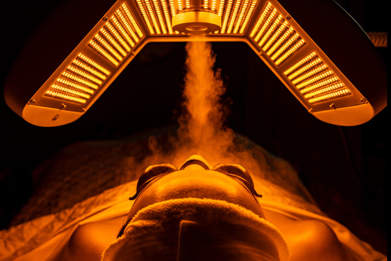 Client lying down while receiving steaming light therapy treatment with goggles to protect eyes